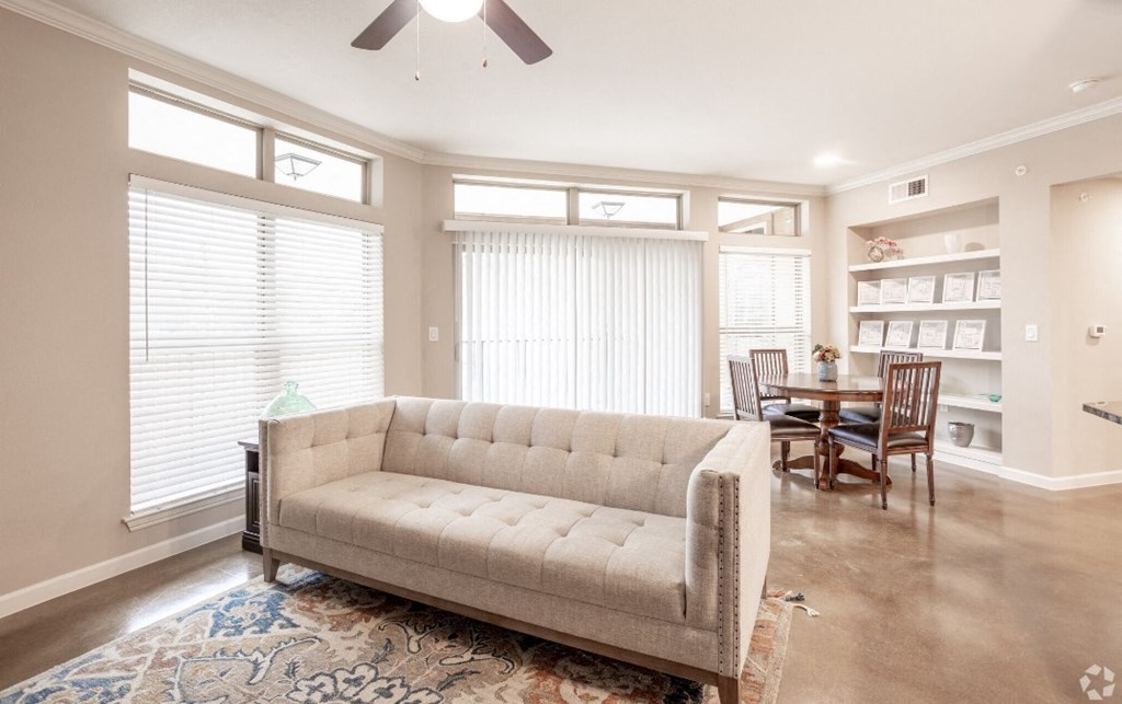 a living room with a couch and a dining room with windows