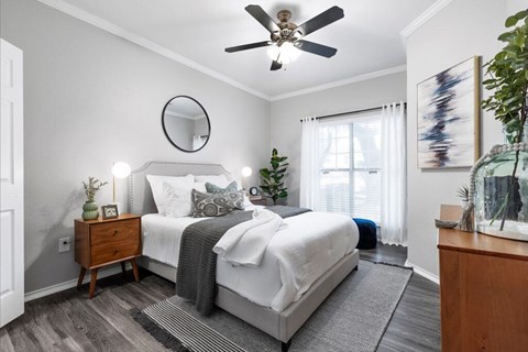 A bedroom with a large bed, a ceiling fan, and a mirror.