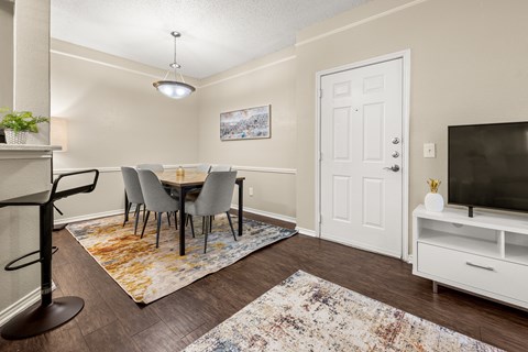 A dining room with a white door and a television on a stand.
