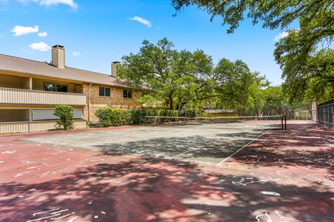 A tennis court is located in front of a house.