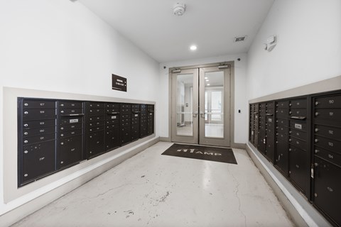 A hallway with black lockers on both sides and a mat on the floor that says "STAFF".