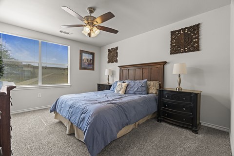 A bedroom with a bed, dresser, and ceiling fan.