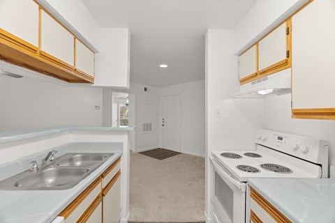 A kitchen with white cabinets and a white stove top oven.