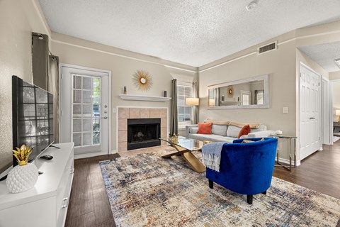 A living room with a fireplace and a blue ottoman.