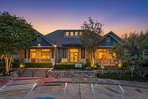 A house with a stone wall and a driveway in front.