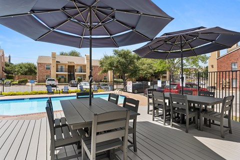 A patio with a table and chairs overlooking a pool.
