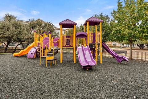 A playground with a purple slide and yellow structure.