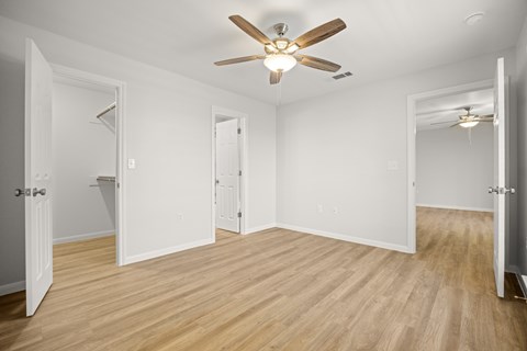 A room with a ceiling fan and wooden flooring.