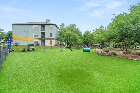 A green lawn in front of a grey building with a yellow stripe.