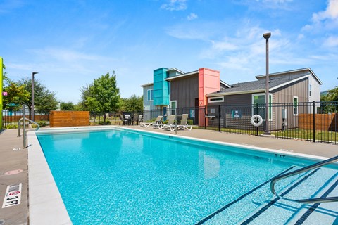A swimming pool surrounded by a black fence with a lifebuoy hanging on it.