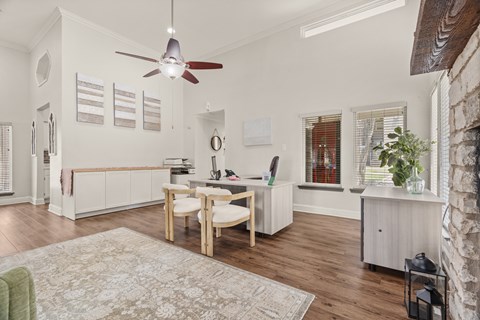 A room with a table and chairs in the center with a rug on the floor.