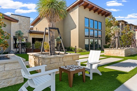 A patio with a table and chairs is in front of a house.