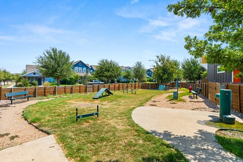 A playground with a green slide and a wooden fence.