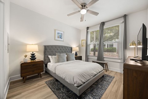 A bedroom with a bed, nightstand, and a ceiling fan.