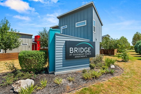 A sign for Bridge at Goodnight Ranch Apartments is in front of a building.