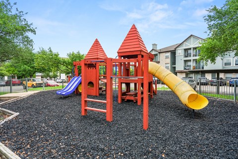 A playground with a red structure and a yellow slide.