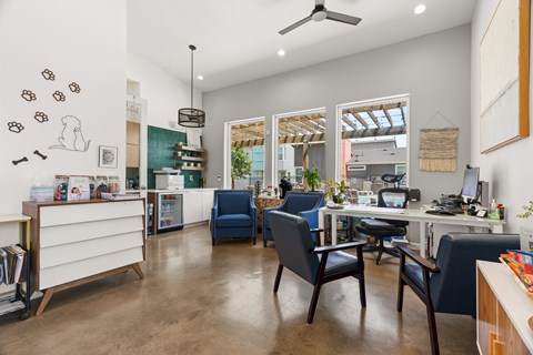 A room with a desk, chairs, and a ceiling fan.