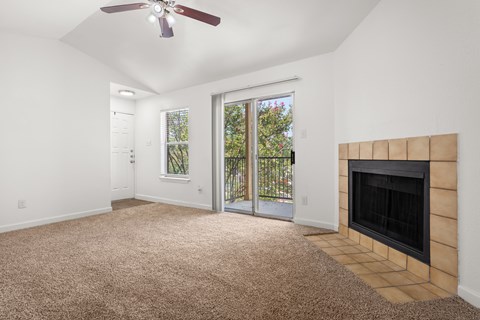 A room with a carpet floor, a fireplace, and a ceiling fan.