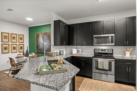 A kitchen with granite countertops and black cabinets.