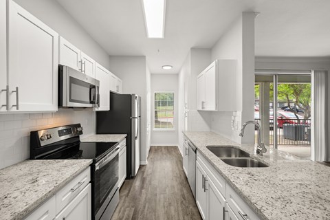 A modern kitchen with granite countertops and stainless steel appliances.