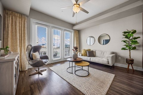 A living room with a chair, a sofa, a table, and a ceiling fan.