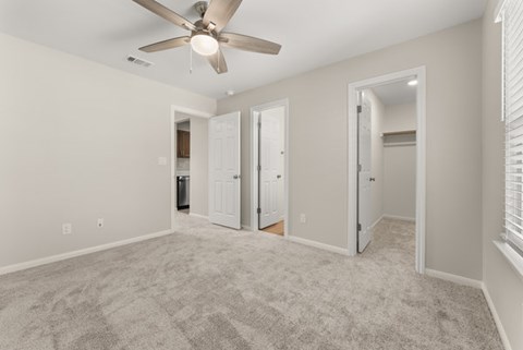 A spacious room with a ceiling fan and carpeted floor.