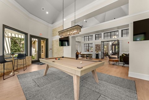 A room with a pool table and a bar area.
