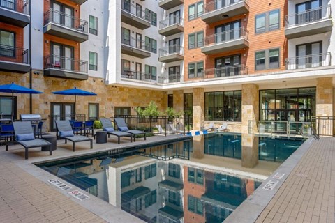 A large pool in front of a building with a glass wall.