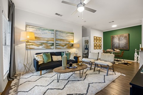 A living room with a black couch, a coffee table, and a painting on the wall.