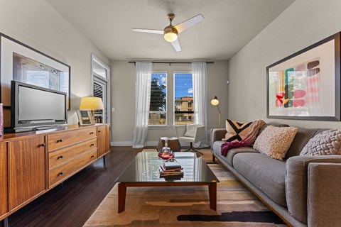 A living room with a grey couch, a wooden cabinet, a coffee table, and a painting on the wall.