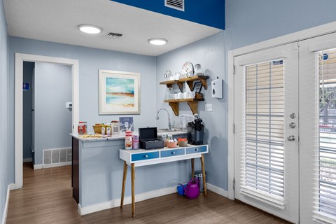 A kitchen area with a table and a shelf with various items on it.