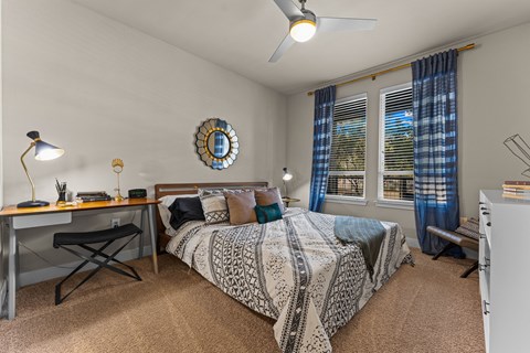 A bedroom with a bed, desk, and chair.