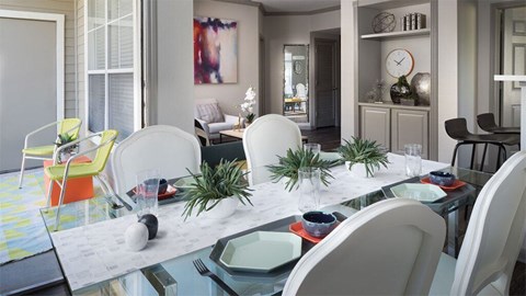 A modern dining room with a glass table and white chairs.