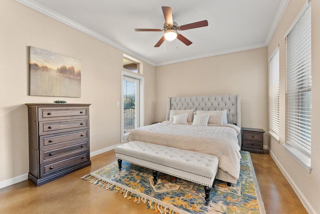 A bedroom with a large bed, a dresser, and a ceiling fan. at Bridge at Heritage Woods, Austin, Texas