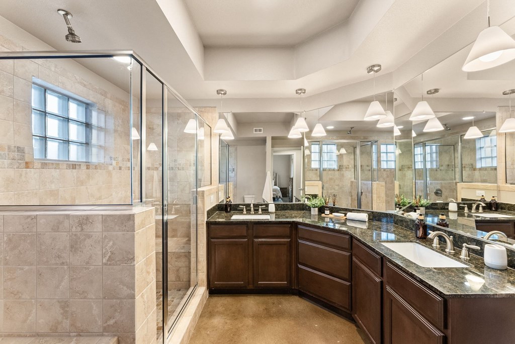 A large, well-lit bathroom with a walk-in shower and double sinks. at Bridge at Heritage Woods, Austin, TX