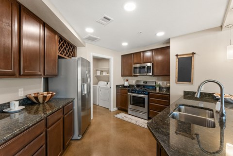 A kitchen with brown cabinets and a black counter top.
