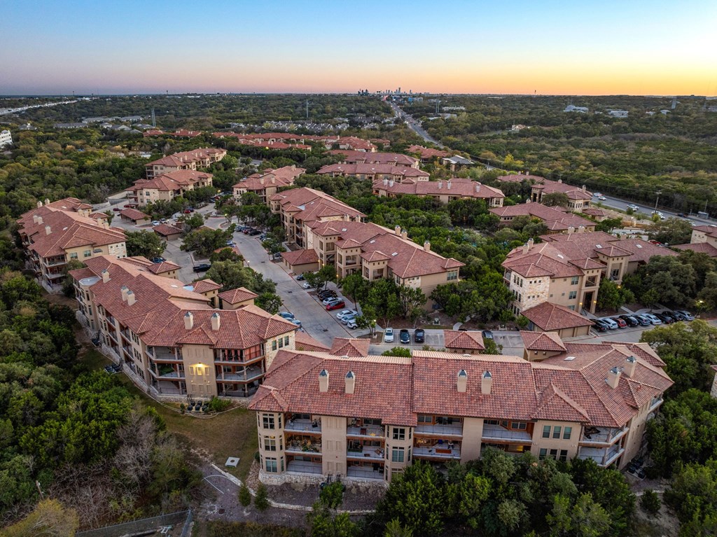 A sunset view of a large residential complex with multiple buildings and parking lots. at Bridge at Heritage Woods, Austin, Texas