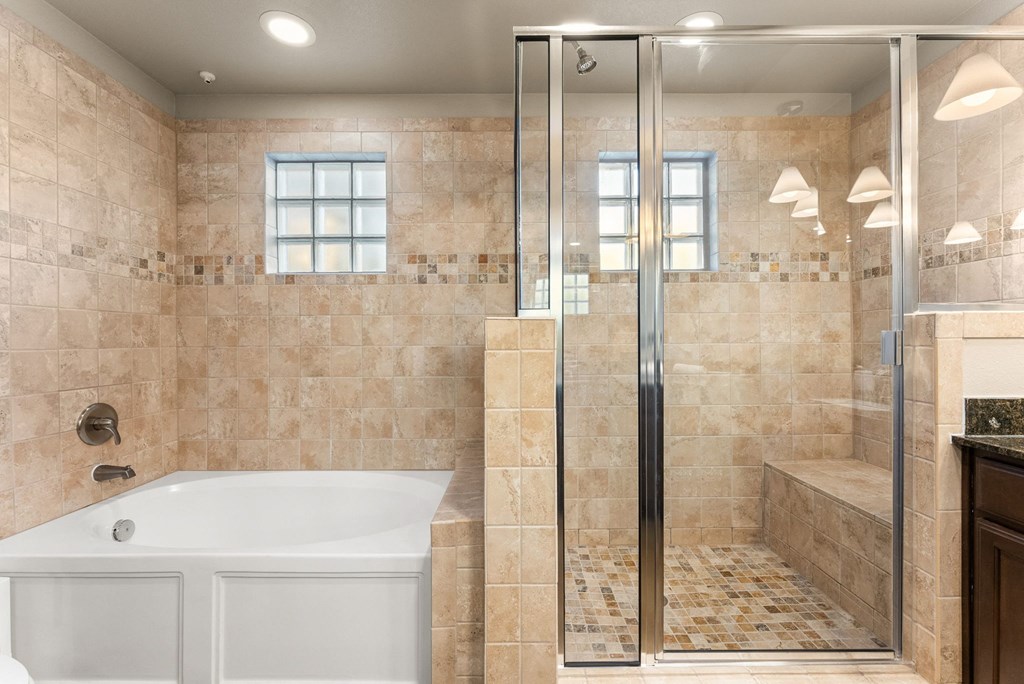 A bathroom with a white tub and a walk-in shower. at Bridge at Heritage Woods, Austin, 78753
