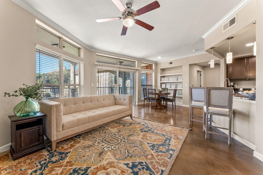 A living room with a beige couch, a rug, and a ceiling fan. at Bridge at Heritage Woods, Austin, 78753