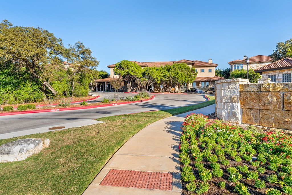 A residential street with houses on both sides and a sidewalk in the foreground. at Bridge at Heritage Woods, Texas, 78753