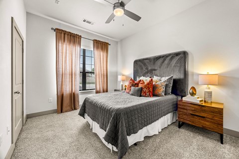 A bedroom with a large bed, a ceiling fan, and a window with curtains. at The Royce at 8100, Austin, 78729