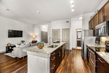 A modern kitchen with wooden floors and stainless steel appliances. at The Royce at 8100, Texas