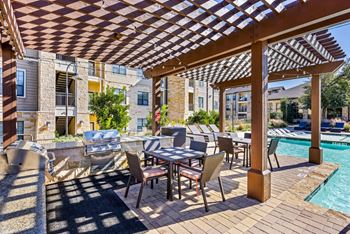 A patio with a table and chairs under a wooden pergola. at The Royce at 8100, Austin, TX, 78729