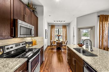 A kitchen with dark wood cabinets and granite countertops. at The Royce at 8100, Austin, TX, 78729