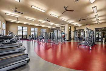 A gym with a red floor and various exercise equipment. at The Royce at 8100, Austin, TX, 78729