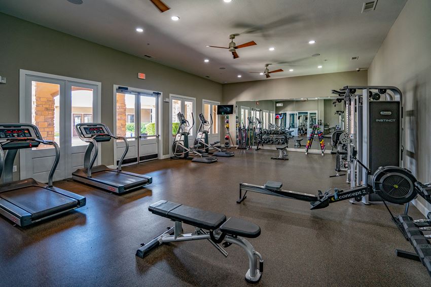 a gym with cardio equipment and weights in a building with windows