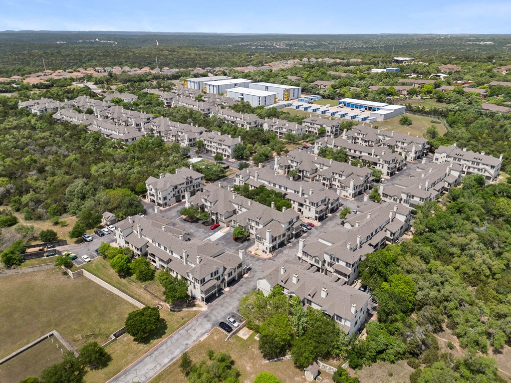 A bird's eye view of a residential area with houses and a large building in the background.