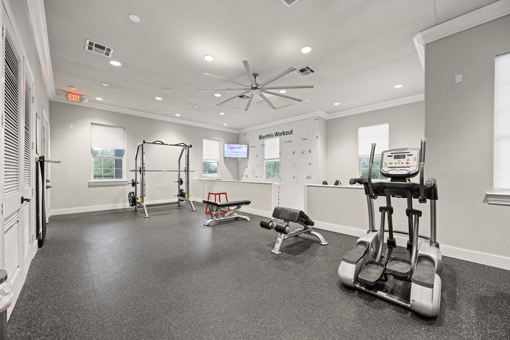 A gym with a variety of equipment including a treadmill, weights, and a bench.