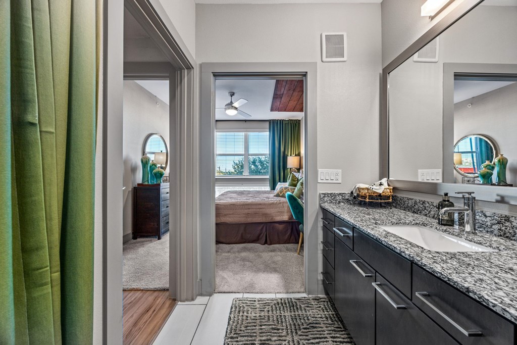 A bathroom with a green curtain and a mirror above the sink. at Bridge at Henley, Texas