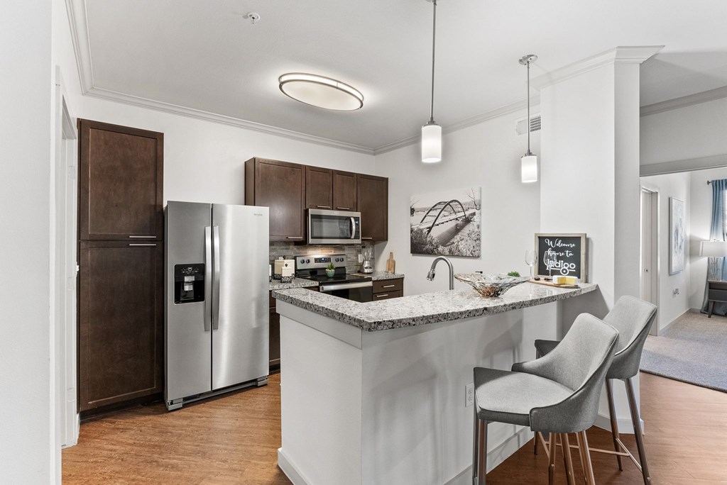 A kitchen with a white island and two chairs. at Bridge at Indigo, Austin, 78717